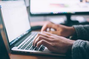 Hands typing on a laptop keyboard
