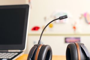 A headset with a microphone attachment on a desk next to an open laptop
