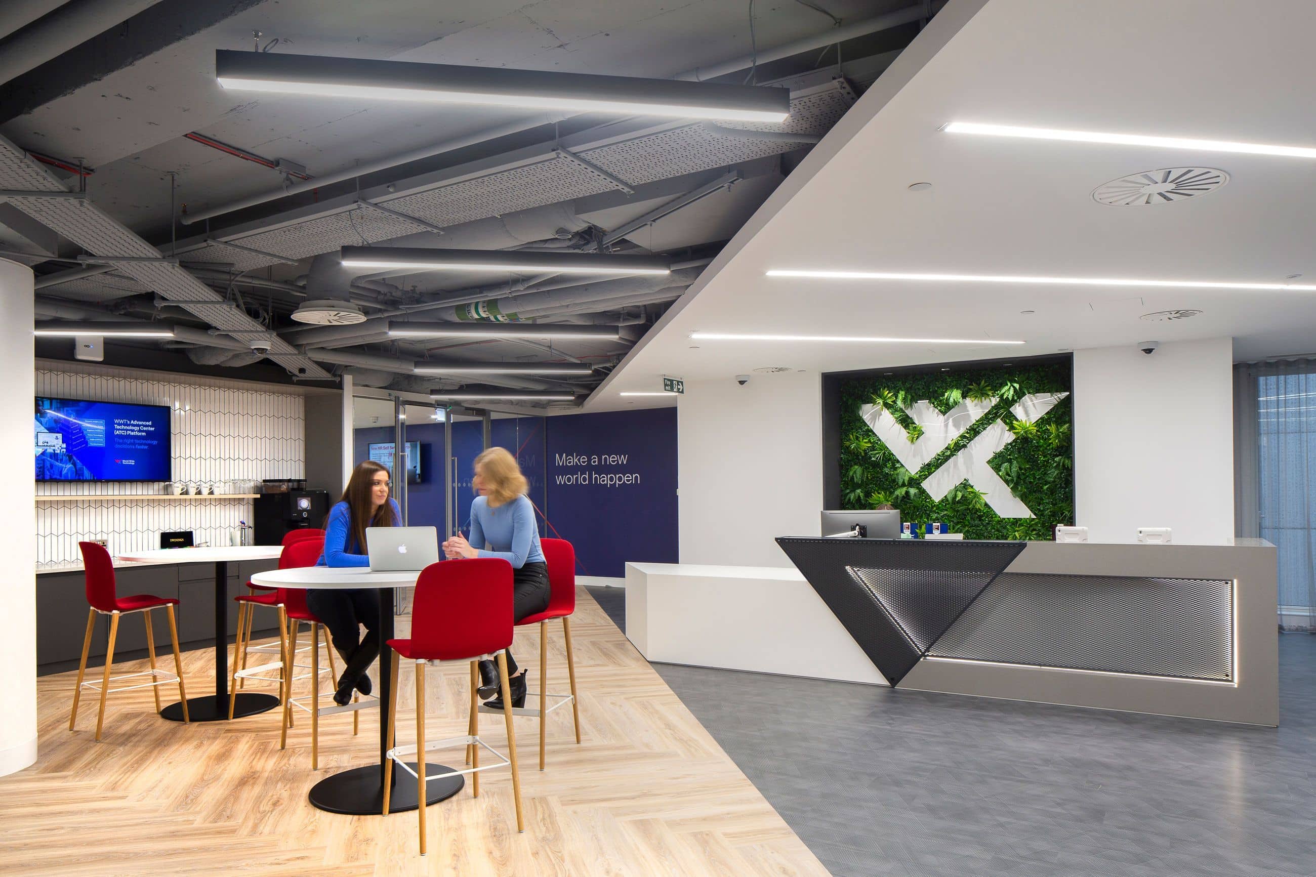 Office lobby with two people at a table, WWT logo behind a front desk in the background.