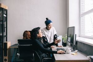 Person showing a colleague something on a monitor in an office. 