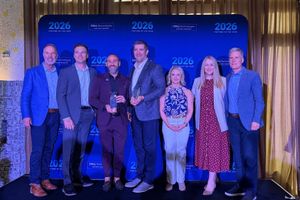Seven people stand on a stage in front of a "2026 Dell Technologies Partner of the Year" backdrop, with two holding award trophies.