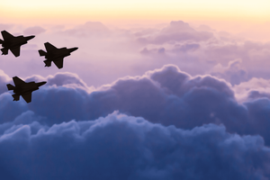 Three fighter jets fly in formation above thick clouds