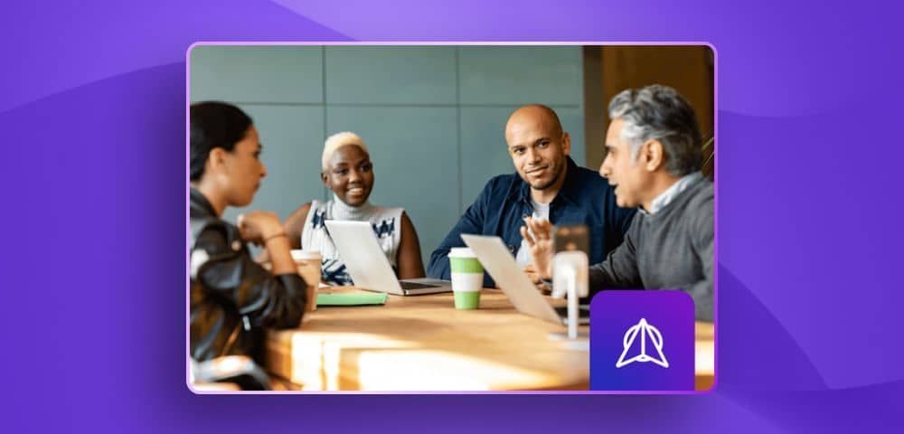 Four professionals in a meeting around a conference table, with a purple logo overlay for WWT Research in the bottom right corner.